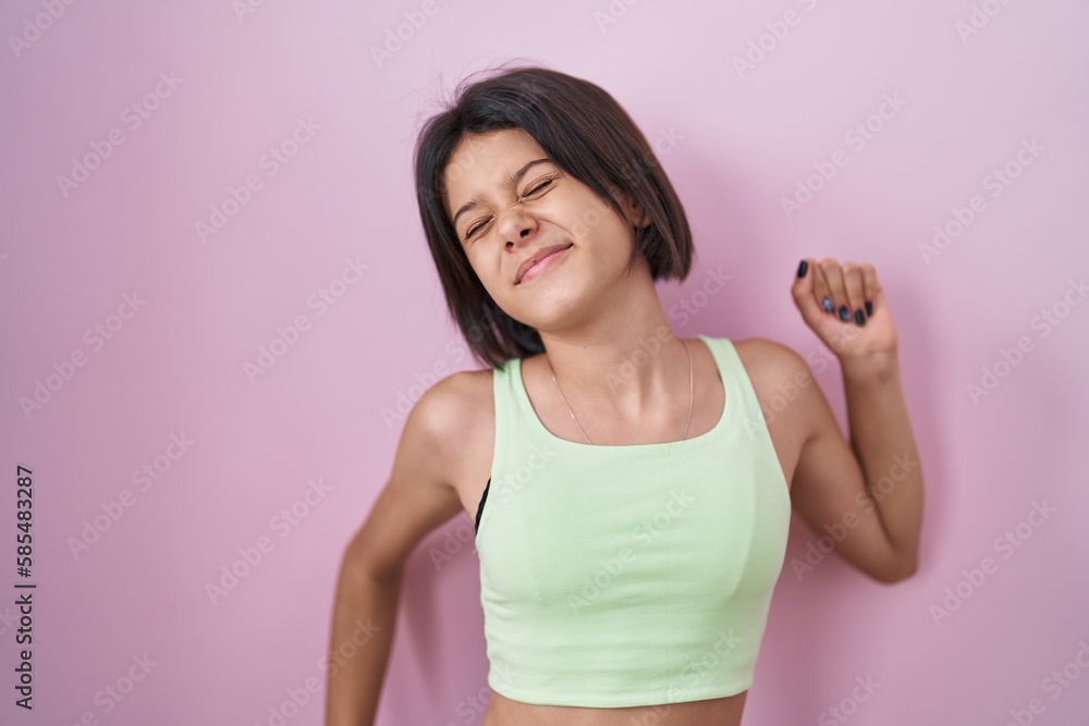 Young girl standing over pink background stretching back, tired and relaxed, sleepy and yawning for early morning Young girl standing over pink background stretching back, tired and relaxed, sleepy and yawning for early morning