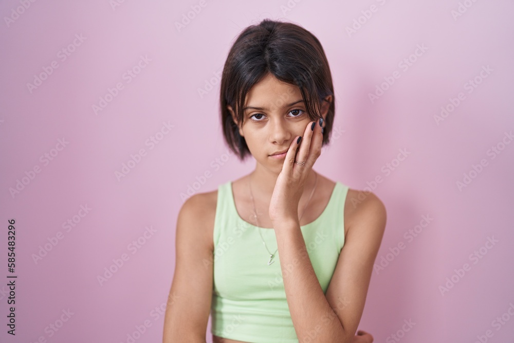Young girl standing over pink background thinking looking tired and bored with depression problems with crossed arms. Young girl standing over pink background thinking looking tired and bored with depression problems with crossed arms.
