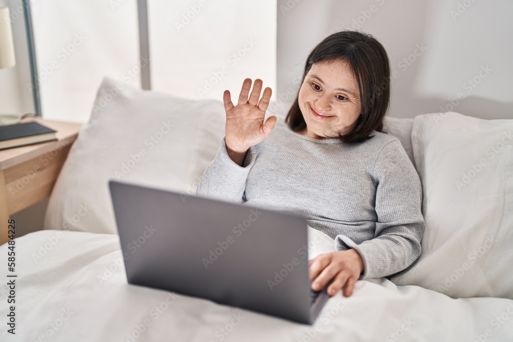 Young woman with down syndrome having video call sitting on bed at bedroom Young woman with down syndrome having video call sitting on bed at bedroom