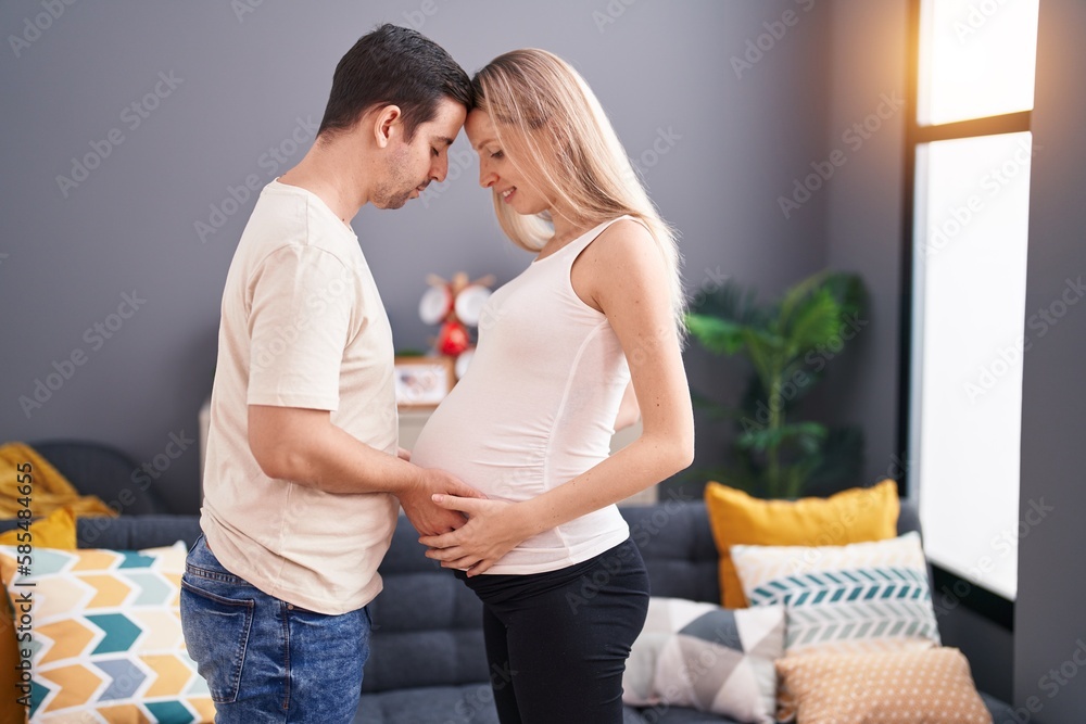 Man and woman couple touching belly standing at home Man and woman couple touching belly standing at home