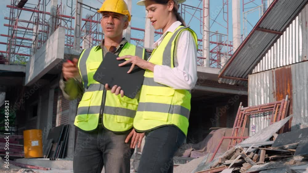 Young engineer man survey and using radio command while worker or architect woman looking digital tablet for planning and talking together at construction site, team contractor, industrial concept. Young engineer man survey and using radio command while worker or architect woman looking digital tablet for planning and talking together at construction site, team contractor, industrial concept.