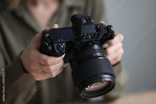 Professional photographer holds camera with big lens