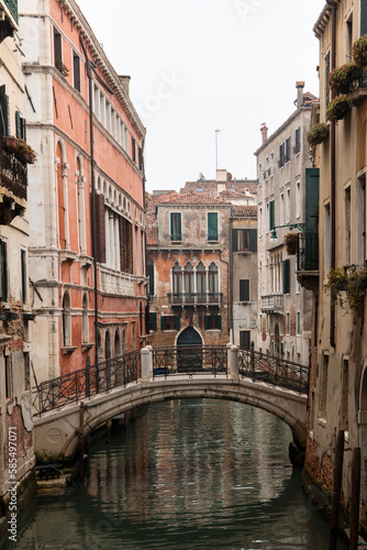 Venice, view of a canal on a misty day, bridge over canal in the background.