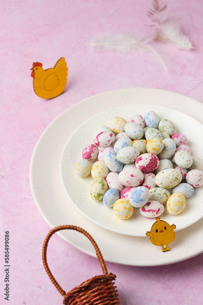 Sugar candy in the form of bird eggs on a white plate on a pink concrete background. Sugar candy in the form of bird eggs on a white plate on a pink concrete background.