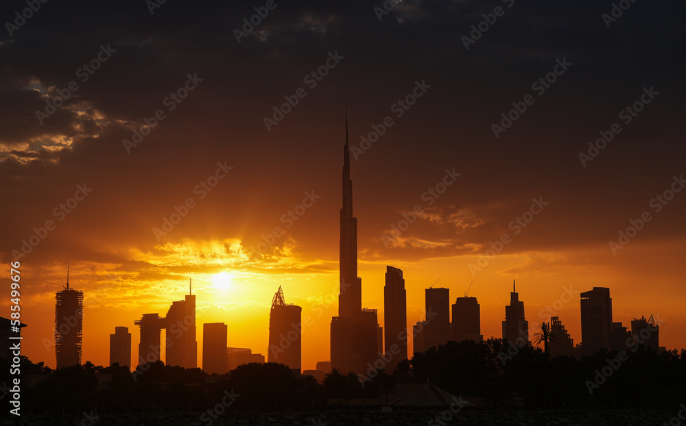 Amazing silhouette sunrise sky in Dubai, view to Burj Khalifa and the entire skyline with modern skyscrapers buildings. Rays of sun bursting in spectacular sunrise landscape in United Arab Emirates.
