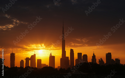 Amazing silhouette sunrise sky in Dubai  view to Burj Khalifa and the entire skyline with modern skyscrapers buildings. Rays of sun bursting in spectacular sunrise landscape in United Arab Emirates.