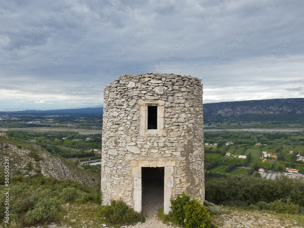 Chappe telegraph tower in stone at Orgon in the Alpilles with a beautiful landscape behind with the green Durance valley under a cloudy sky in Provence in France