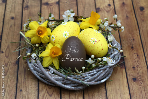 
Tarjeta de felicitación de Pascua feliz: Armoniosa decoración de Pascua con narcisos y huevos de Pascua en un nido, uno de los cuales tiene escrito el texto Feliz Pascua. photo