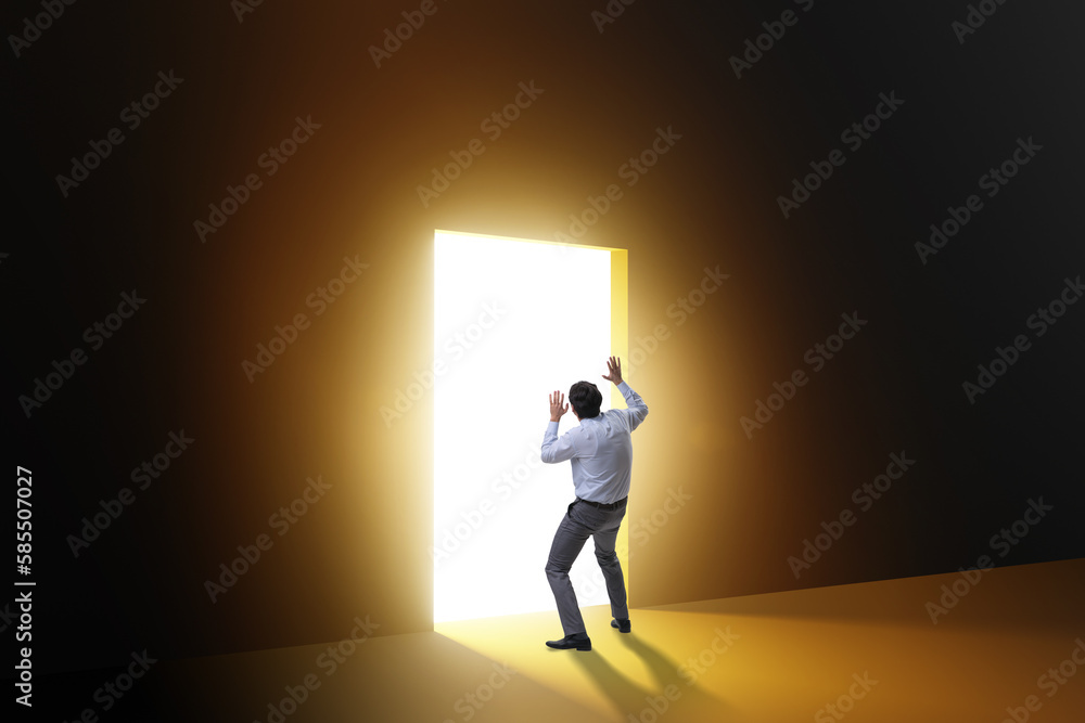 Businessman entering backlit door in escape concept Businessman entering backlit door in escape concept