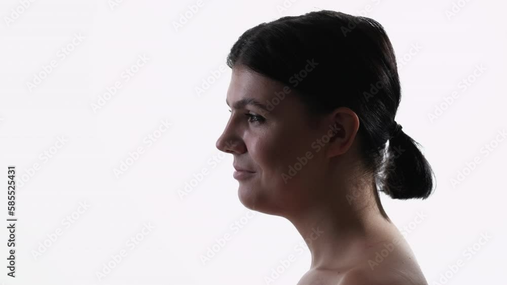 Female model. Silhouette portrait. Profile view. Smiling brunette lady with neutral makeup and short hair tail posing white background. Female model. Silhouette portrait. Profile view. Smiling brunette lady with neutral makeup and short hair tail posing white background.