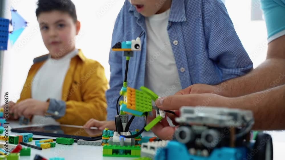Robotics programming class. Children construct and code Robot. STEM education using constructor blocks and laptop tablet, remote control joystick. Technology educational development for school kids. Robotics programming class. Children construct and code Robot. STEM education using constructor blocks and laptop tablet, remote control joystick. Technology educational development for school kids.