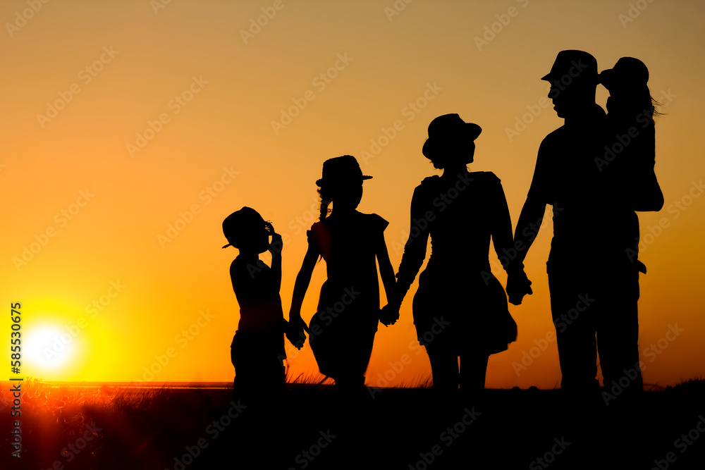 Fototapeta premium A Happy family by the sea at sunset in travel silhouette in nature