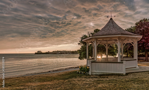 Niagara-on-the-Lake, Ontario, Canada: - July 9, 2016: Sunrise at Queen's Royal Park with the gazebo under a dramatic  sky and Fort Niagara in the distance photo