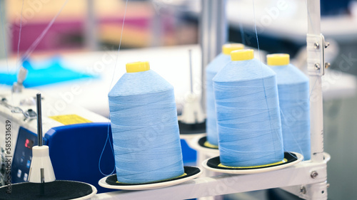 Reels of textile yarn blue thread at industrial weaving manufacturing machine,  textile fabric production industrial concept background