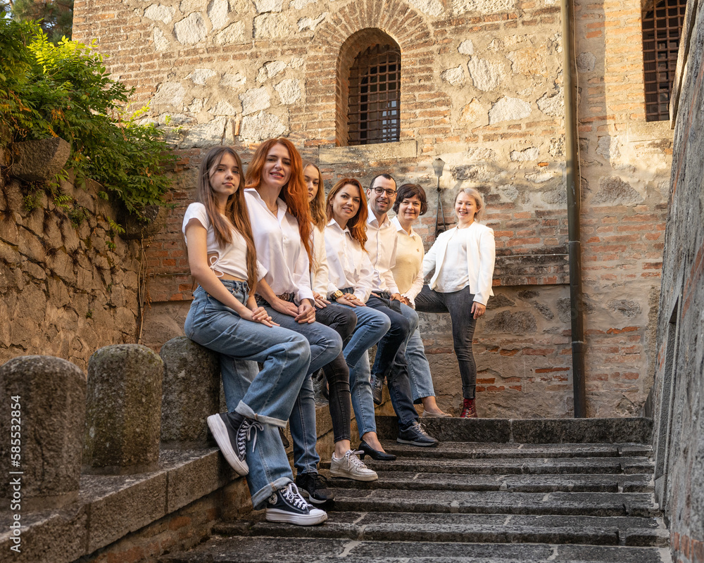 A company of 7 people poses in the morning light on the old steps, Italy