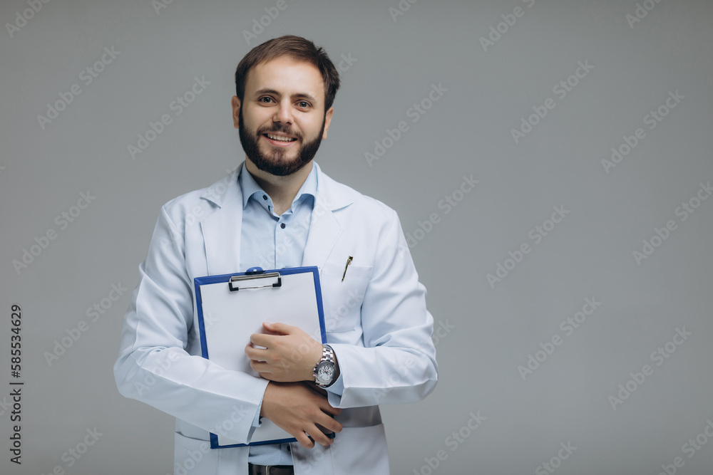 Medical Internship. Portrait Of Happy Male Doctor Student In Uniform Holding Clipboard In Hands And Posing Over Light Background, Panorama. Medical Internship. Portrait Of Happy Male Doctor Student In Uniform Holding Clipboard In Hands And Posing Over Light Background, Panorama.