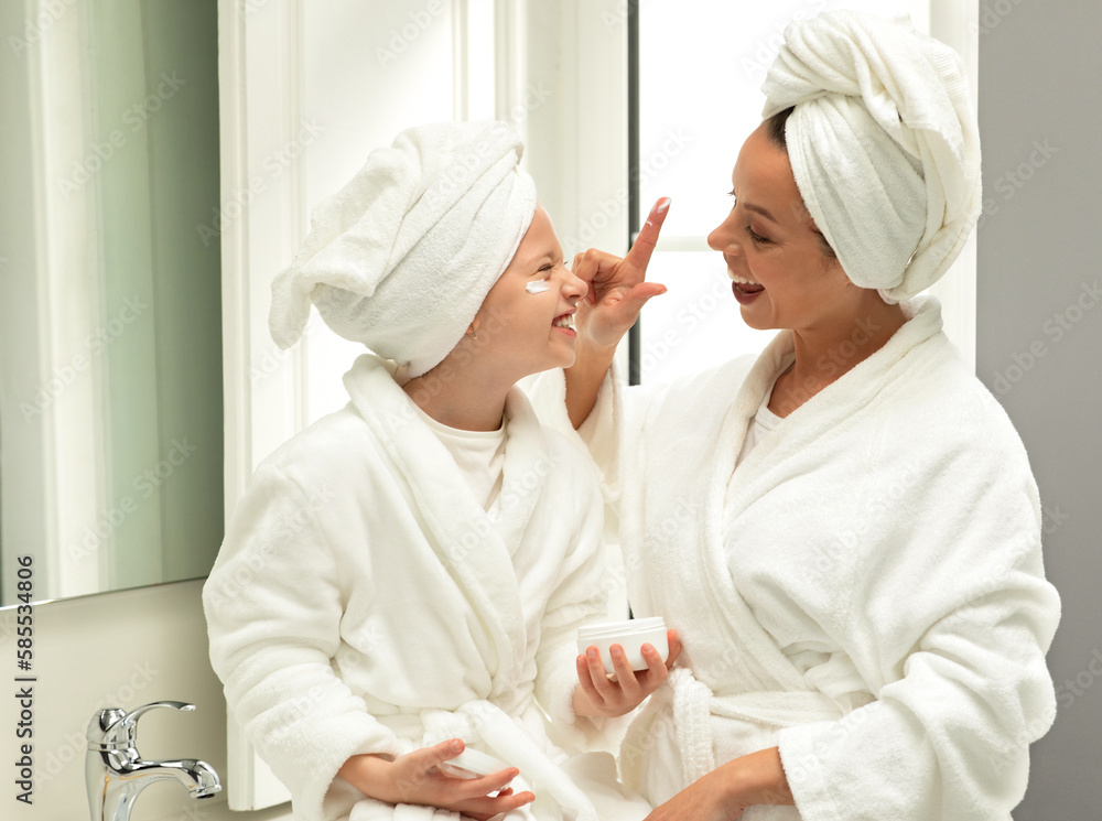 Glad caucasian teen and young mom in bathrobe and towel, have fun, apply cream, enjoy beauty care Glad caucasian teen and young mom in bathrobe and towel, have fun, apply cream, enjoy beauty care