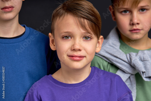 brownhaired handsome boy with greeen eyes posing to camera, his serious attractive brothers in th ebcakground of photo cropped portrait. friendship. leader among classmates photo