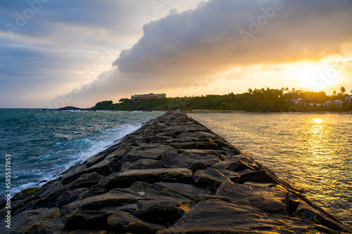 Beautiful coast with a stone dam at sunset. Contrasting bright sky. Photography for the background of tourism, design and advertising