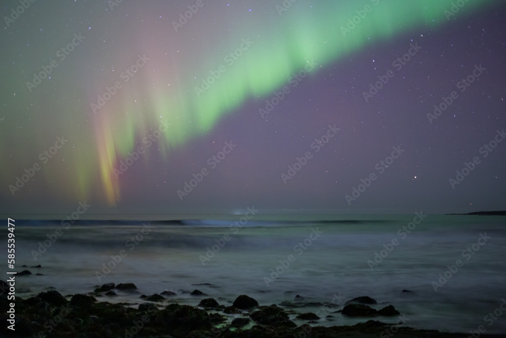 Aurora borealis over breaking waves calm purple sky