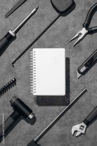 Flat lay composition with set of home repair tools and opened notebook on grey stone background. Top view pattern with copy space.