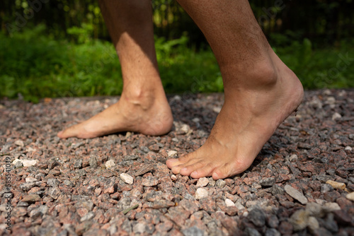 A man walks barefoot on small stones