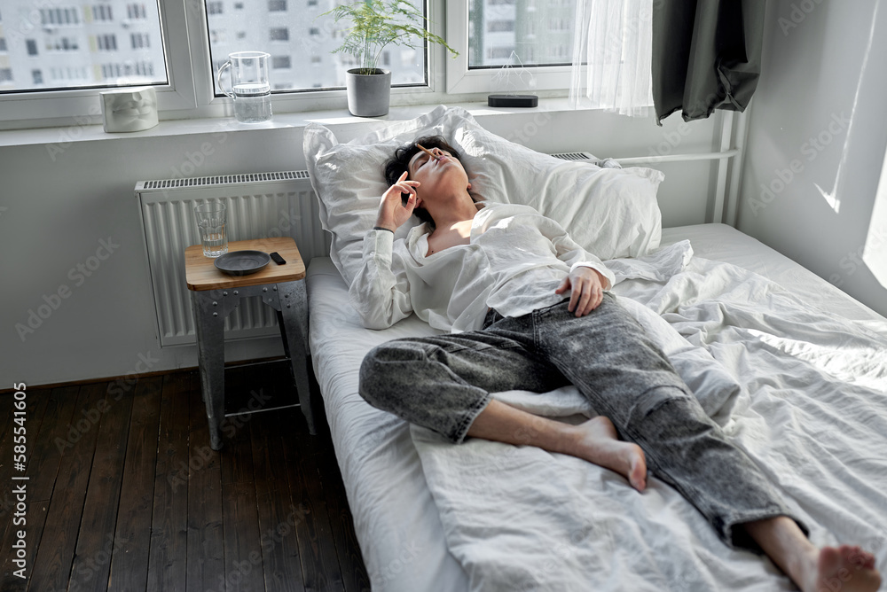 Fototapeta premium Alcoholic male smoking alone at home,full length shot. loneliness, depression, bad habits, laziness. freedom