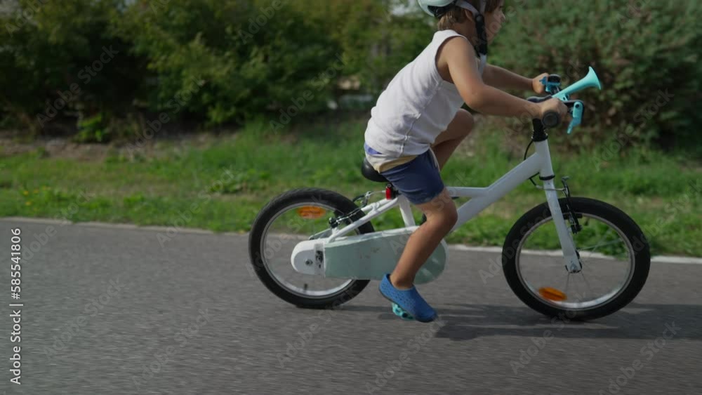 Kid exercising outdoors riding bicycle and wearing helmet. Active boy rides bike in sunny day Kid exercising outdoors riding bicycle and wearing helmet. Active boy rides bike in sunny day
