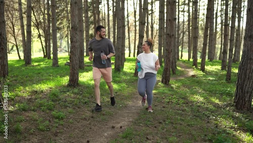 Beautiful overweight female jogging with her friend through the forest.