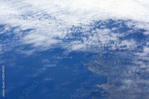 Flying over white clouds and blue sea. Earth satellite view