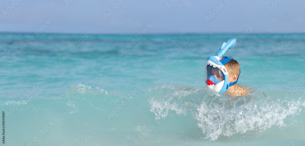 A little boy in a full face mask is snorkeling in the Maldives. Banner with copy space
