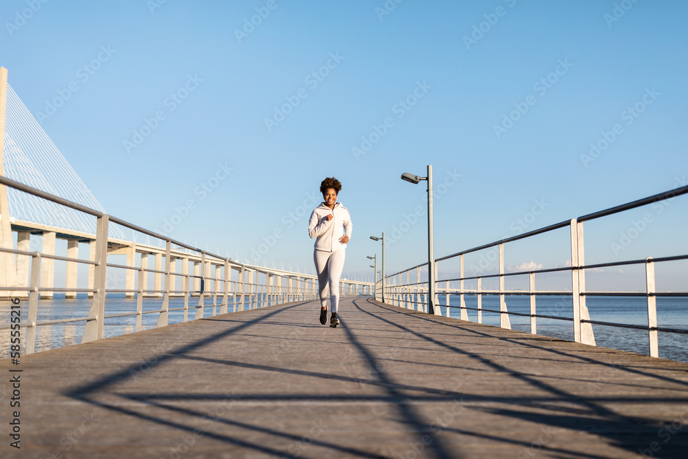 Outdoor Sports. Happy Young Black Female Running On Pier Near Sea