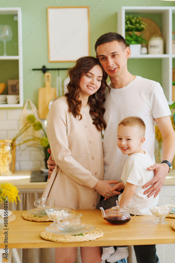 a loving family. pregnant mom, son and dad In the kitchen. a cozy house a loving family. pregnant mom, son and dad In the kitchen. a cozy house