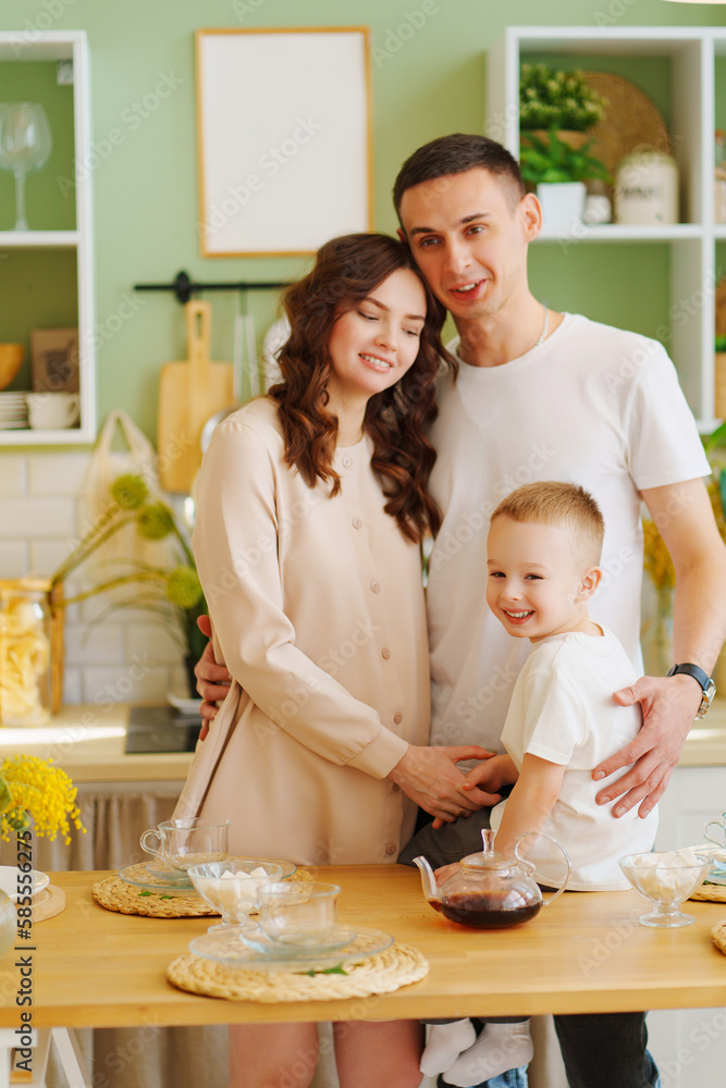 a loving family. pregnant mom, son and dad In the kitchen. a cozy house 