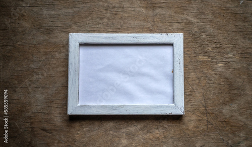 Photo of an empty wooden frame in the style of shabby chic on a wooden background.A clean white horizontal frame for placing the photo.