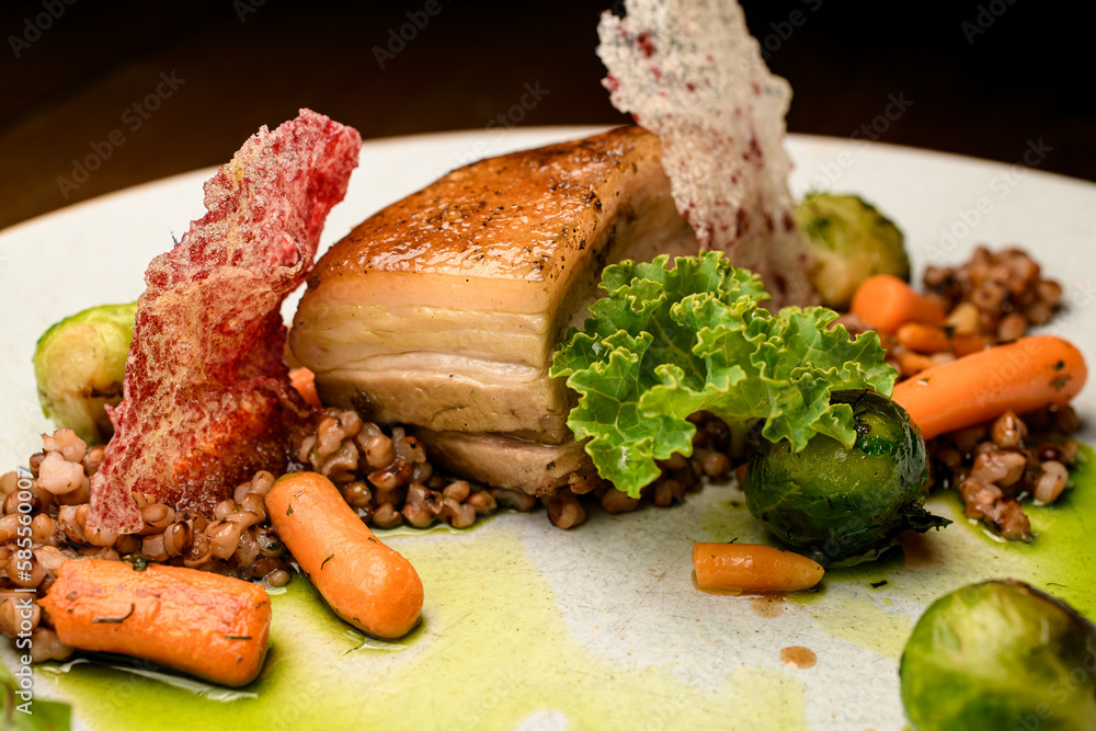 Close-up on piece of baked pork meat with buckwheat and vegetables on plate Close-up on piece of baked pork meat with buckwheat and vegetables on plate