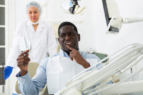 African american patient checks cured teeth with a mirror