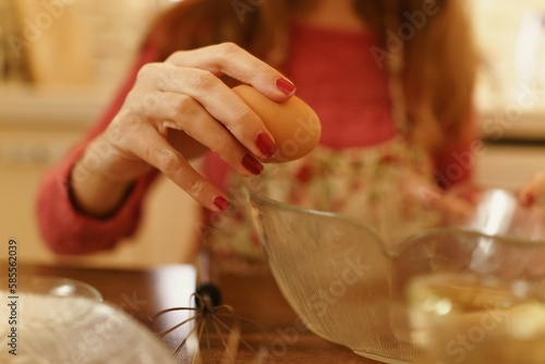 Close-up shot of making cookies while breaking eggs into a bowl. Detail photo with only hands visible when breaking eggs.