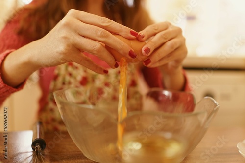 Close-up shot of making cookies while breaking eggs into a bowl. Detail photo with only hands visible when breaking eggs.