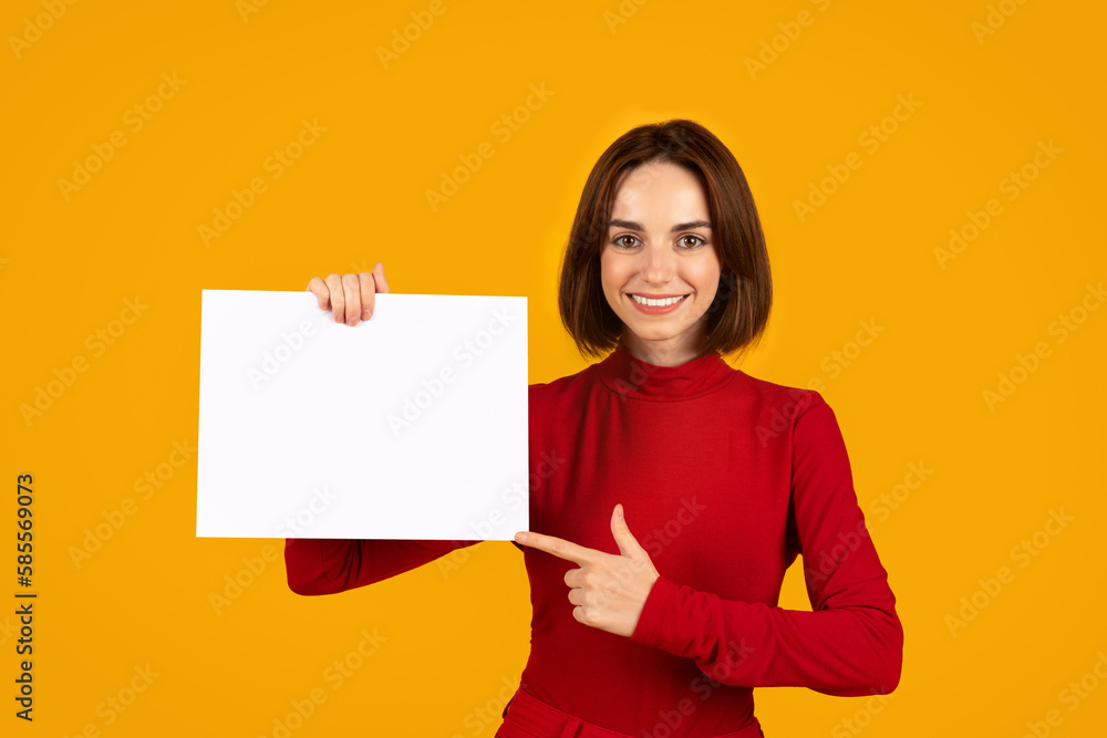 Happy beautiful young woman in red pointing at empty placard Happy beautiful young woman in red pointing at empty placard