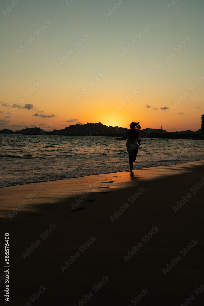 beautiful woman enjoying the beach and an incredible sunset against light