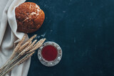 Bread, wine and ears of wheat on a dark background, communion concept