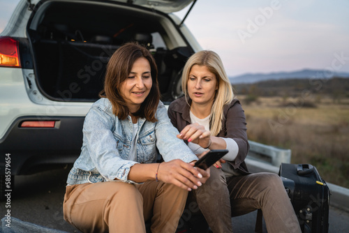 two women check mobile phone map app for direction on travel vacation © Miljan Živković