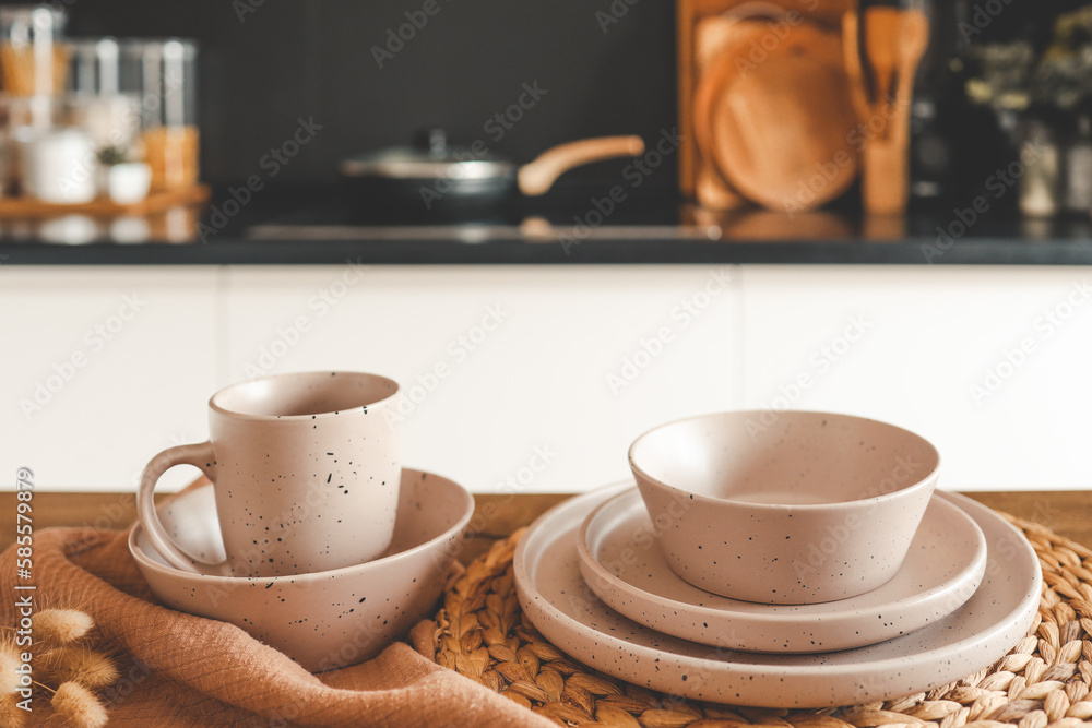 Set of beige minimalist dishes on a table against the backdrop of a kitchen Set of beige minimalist dishes on a table against the backdrop of a kitchen