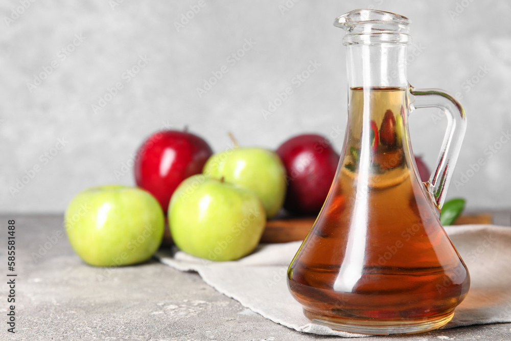 Glass bottle of fresh apple cider vinegar and fruits on grey grunge table Glass bottle of fresh apple cider vinegar and fruits on grey grunge table
