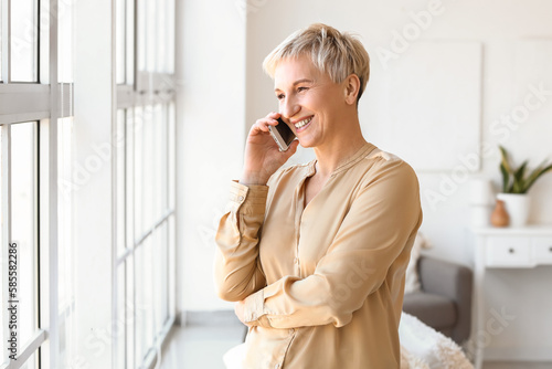 Mature woman talking by mobile phone at home