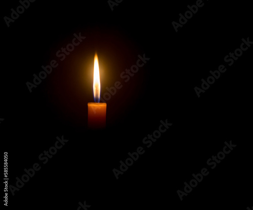 A single burning candle flame or light glowing on an orange cand