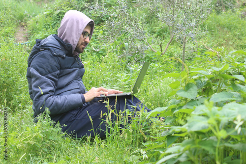Man working outdoors with laptop sitting in nature. Concept of remote work or freelancer lifestyle. Cellular network broadband coverage. internet 5G. 