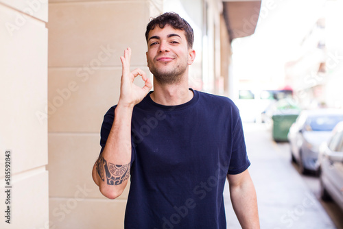 young handsome man feeling happy, relaxed and satisfied, showing approval with okay gesture, smiling