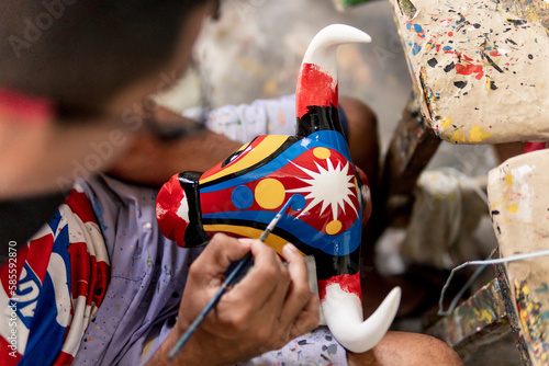 man painting bull mask carved in wood and painted with commemorative colors of the carnival of barranquilla colombia